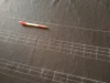 Chalk lines on linen A strip of black linen with straight lines marked out in chalk.