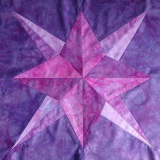 A double star pieced together from fabric in variegated shades of purple and pink.